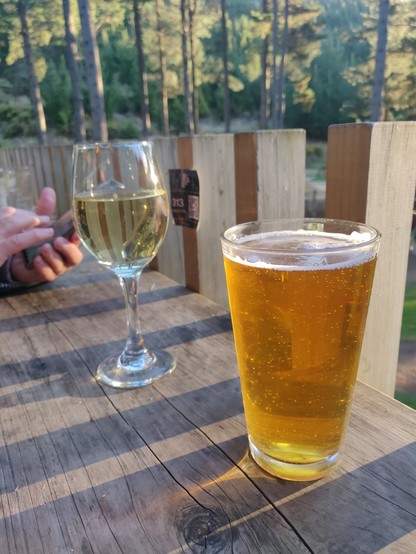A hoppy APA beer and a Chardonnay on a wooden outdoor bar with evening sun shining through... 