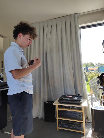 Mr 14, standing side on in his school uniform with phone recording this epic experience: excited to be hearing his first LP for the first time. This is in our lounge with Tannoy speakers on the floor, cobbled together speaker cables, and stereo components (Yamaha power amp & radio receiver, Onkyo turntable, and Technics dual cassette deck. Incidentally, the latter was bought from Lan Pham's husband 7-8 yrs ago) in a home made ply rack sitting on the carpet in front of curtains blocking out the …